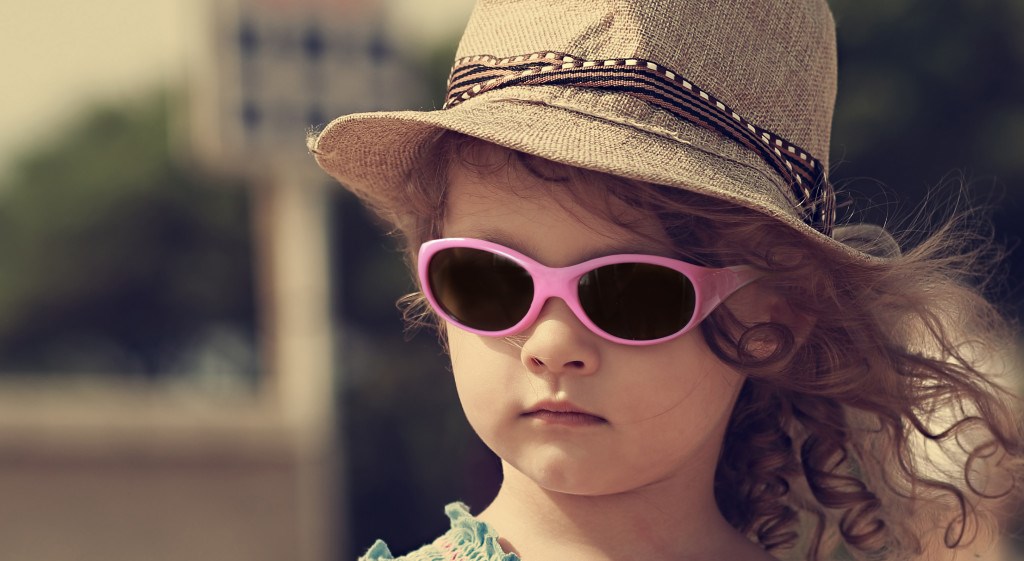 Kid in sun glasses and fashion hat outdoors. Vintage