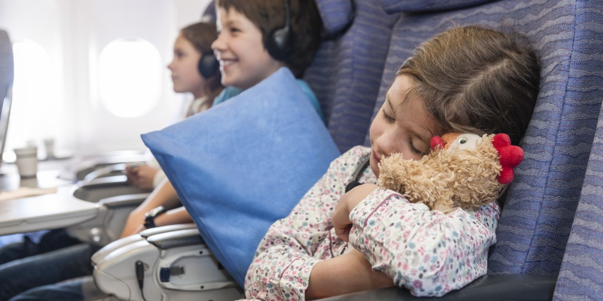 Girl sleeping on airplane holding stuffed animal